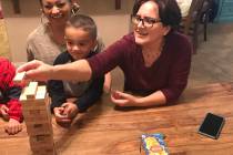 Angelica Rodriguez, 62, plays the game Jenga with one of her 12 grandchildren and her daughter, ...