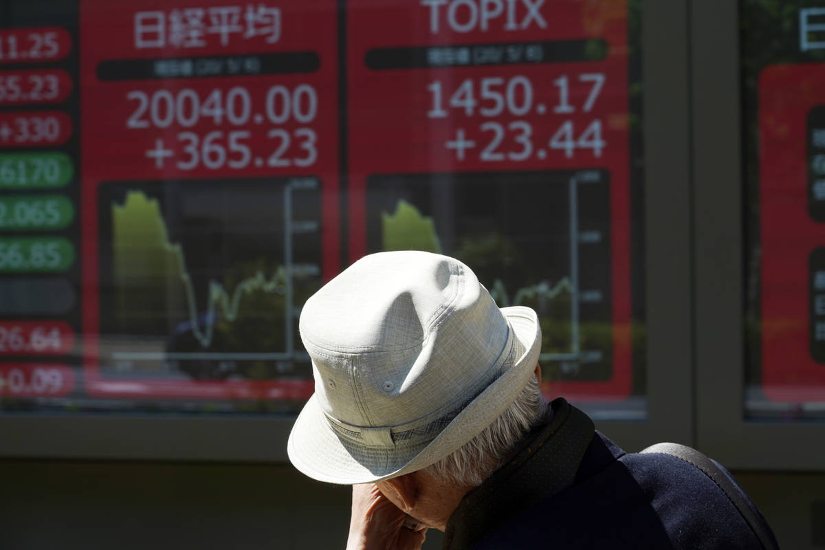 A man walks past an electronic stock board showing Japan's Nikkei 225 index at a securities fir ...