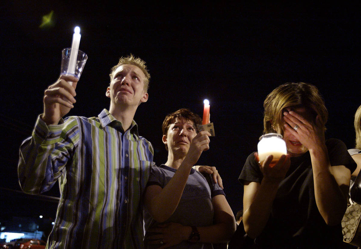 From left, Brad Barnes, Andrea Deashiell and Elizabeth Auten cry as they hold candles during a ...