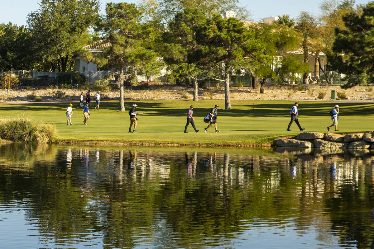 Golfers make their way up the fairway at hole 16 past a water feature during the third round of ...