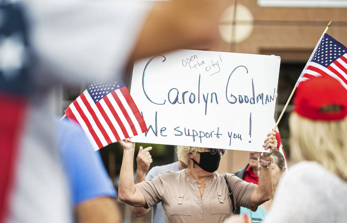 Protesters hold signs supporting Mayor Carolyn Goodman's desire to lift state-wide lock down me ...