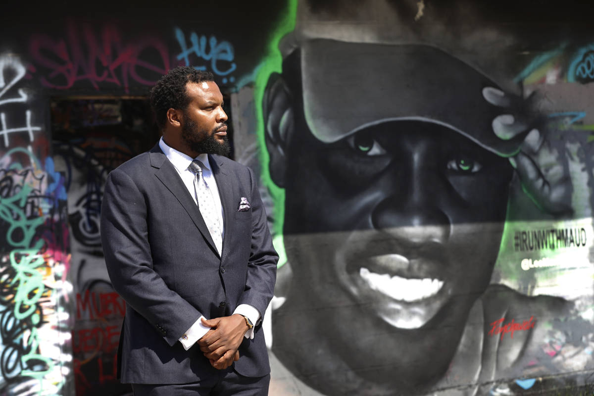 Lee Merritt, a lawyer representing the family of Ahmaud Arbery, poses for a photo by a mural in ...