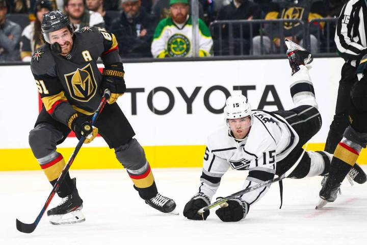 Golden Knights' Mark Stone (61) eyes the puck as Los Angeles Kings' Ben Hutton (15) gets trippe ...