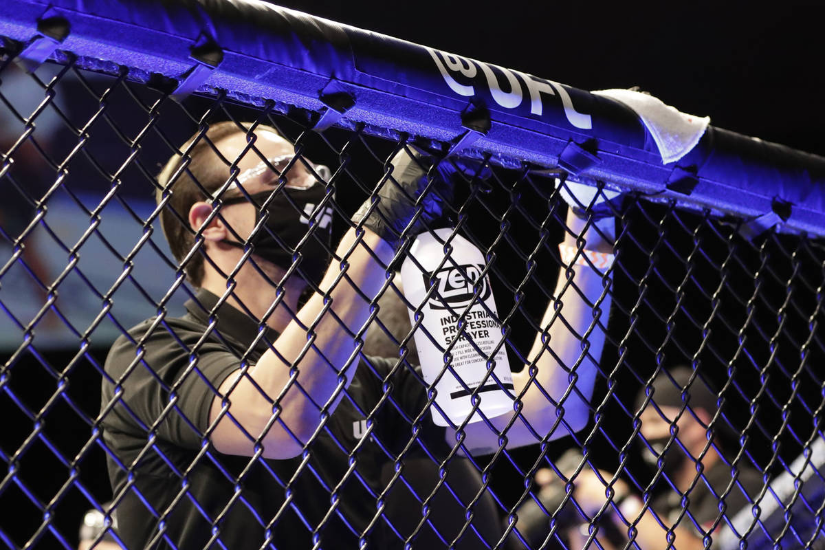 A worker wipes down areas of the octagon between bouts at a UFC 249 mixed martial arts event Sa ...