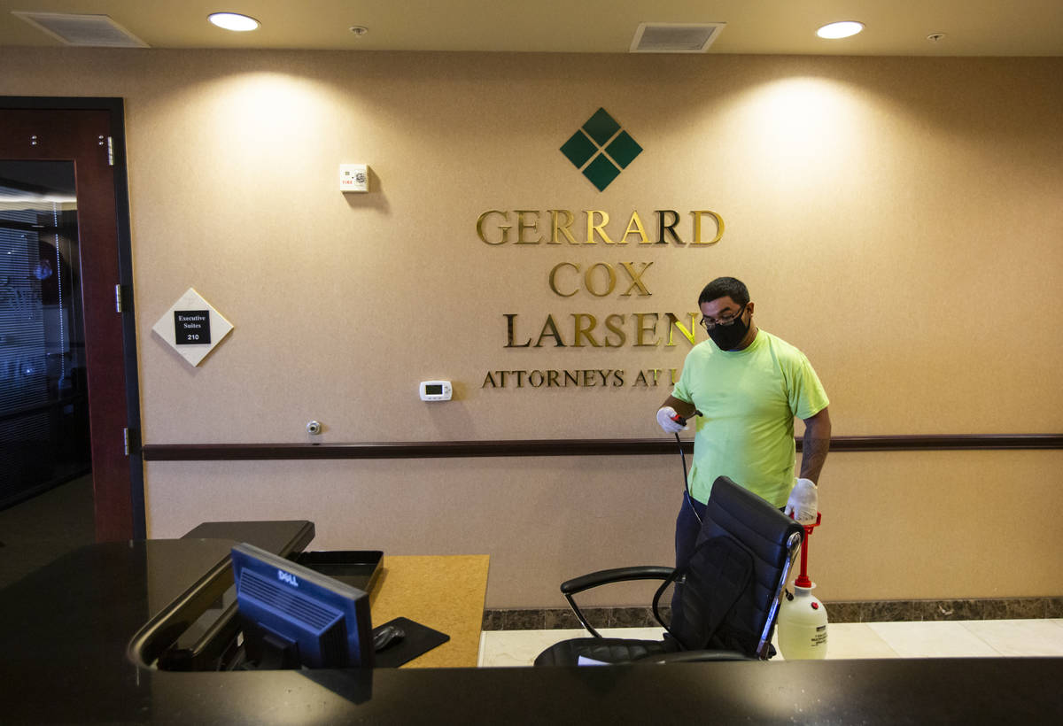 Anuar Flores of CitiClean Services uses a disinfecting mist while cleaning a desk at the Gerrar ...