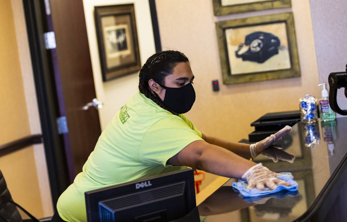 Mayola Lopez of CitiClean Services wipes down a desk in the lobby at the Gerrard Cox Larsen law ...
