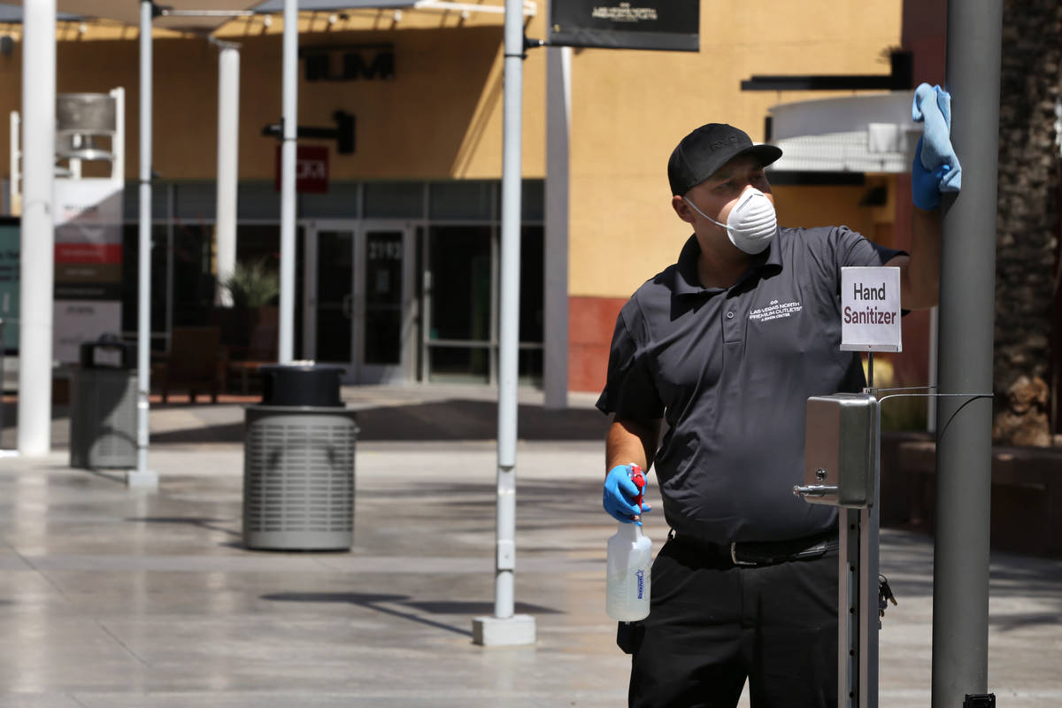 Ivan Leybe cleans about one of the many hand sanitizing stations now installed throughout the L ...