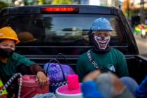 Construction workers wearing face masks travel in a back of a crew cab in Bangkok, Thailand, We ...