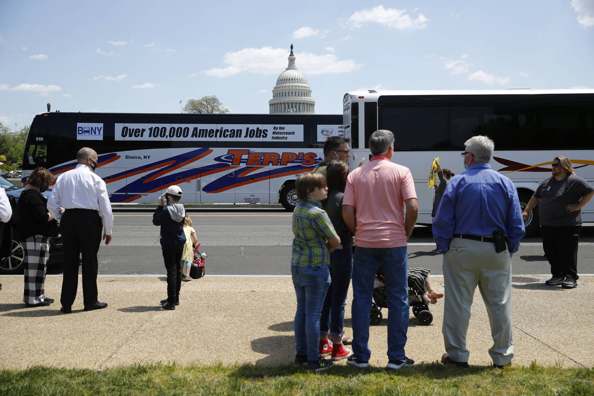 Buses and motor coaches circle past gatherers on the National Mall in Washington, Wednesday, Ma ...