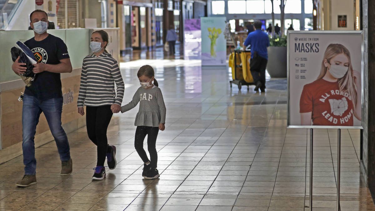 Shoppers walks past a sign encouraging masks at SouthPark Mall, Wednesday, May 13, 2020, in Str ...