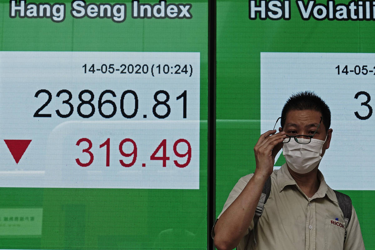 A man wearing face mask walks past a bank electronic board showing the Hong Kong share index at ...