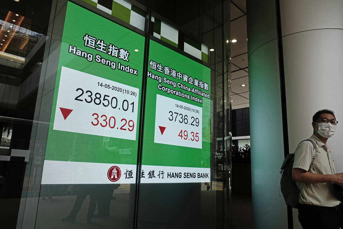 A man wearing face mask walks past a bank electronic board showing the Hong Kong share index at ...