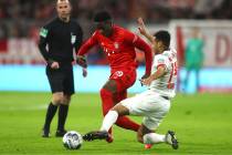 Bayern's Alphonso Davies, centre, and Leipzig's Tyler Adams challenge for the ball during the G ...