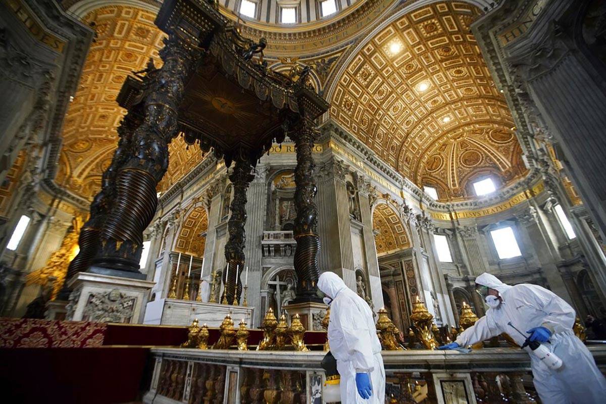 Workers in protective gear sanitize beneath the baroque sculpted bronze canopy of St. Peter's B ...