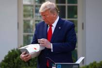 In a March 30, 2020, file photo, President Donald Trump opens a box containing a 5-minute test ...