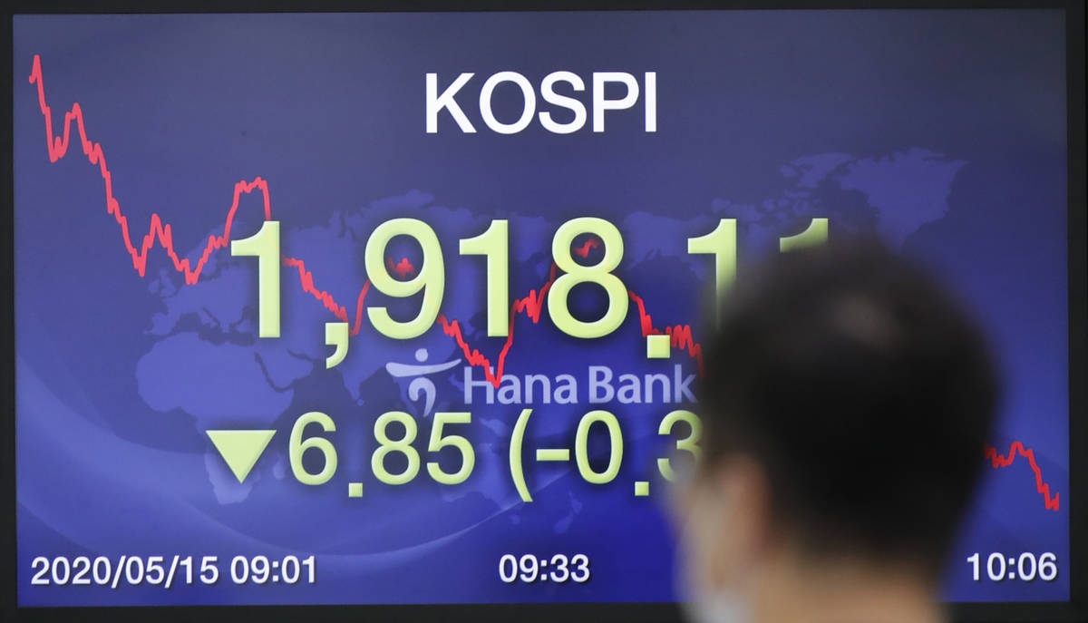A currency trader walks near a screen showing the Korea Composite Stock Price Index (KOSPI) at ...