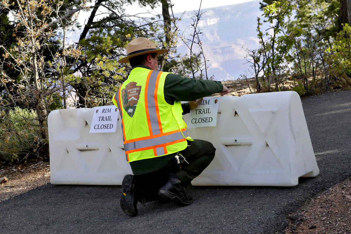 A Park Ranger blocks off a trail along Rim Drive at the Grand Canyon Friday, May 15, 2020, in G ...