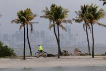 The Miami skyline is shrouded in clouds as a cyclist rides along Biscayne Bay at Matheson Hammo ...
