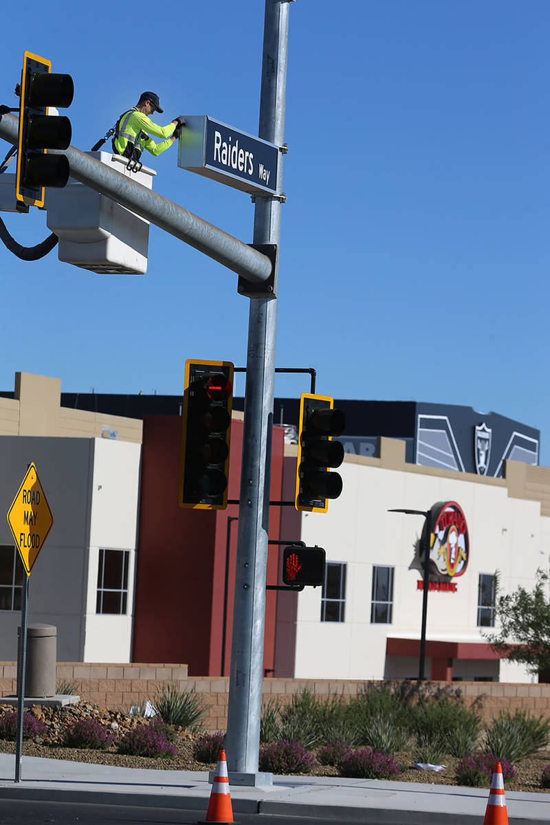 Justin Buhl, traffic signal technical for the City of Henderson, installs a Raiders Way street ...