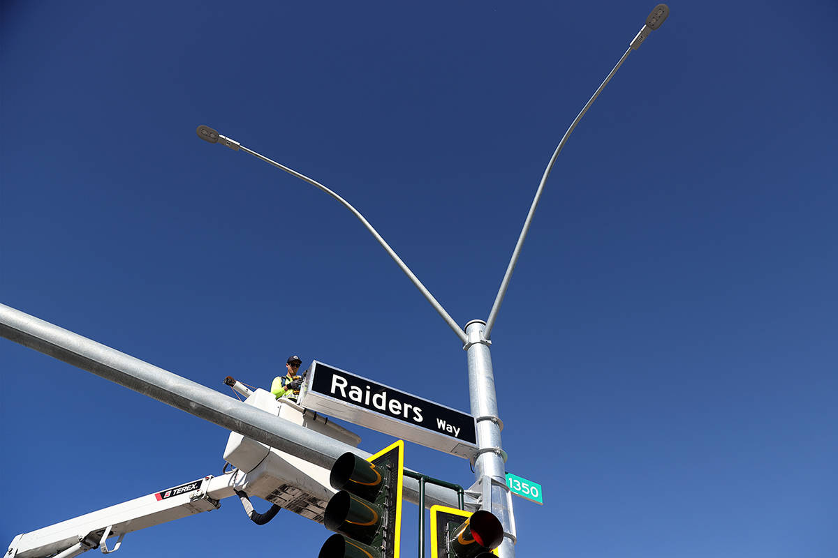 Justin Buhl, traffic signal technical for the City of Henderson, installs a Raiders Way street ...