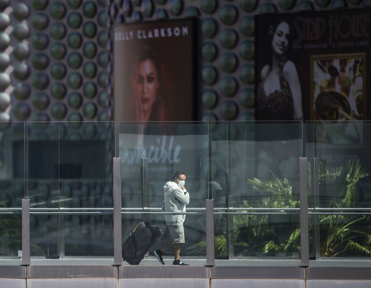 Tourists wearing medical masks make their way along the Strip on Tuesday, March 17, 2020, in La ...