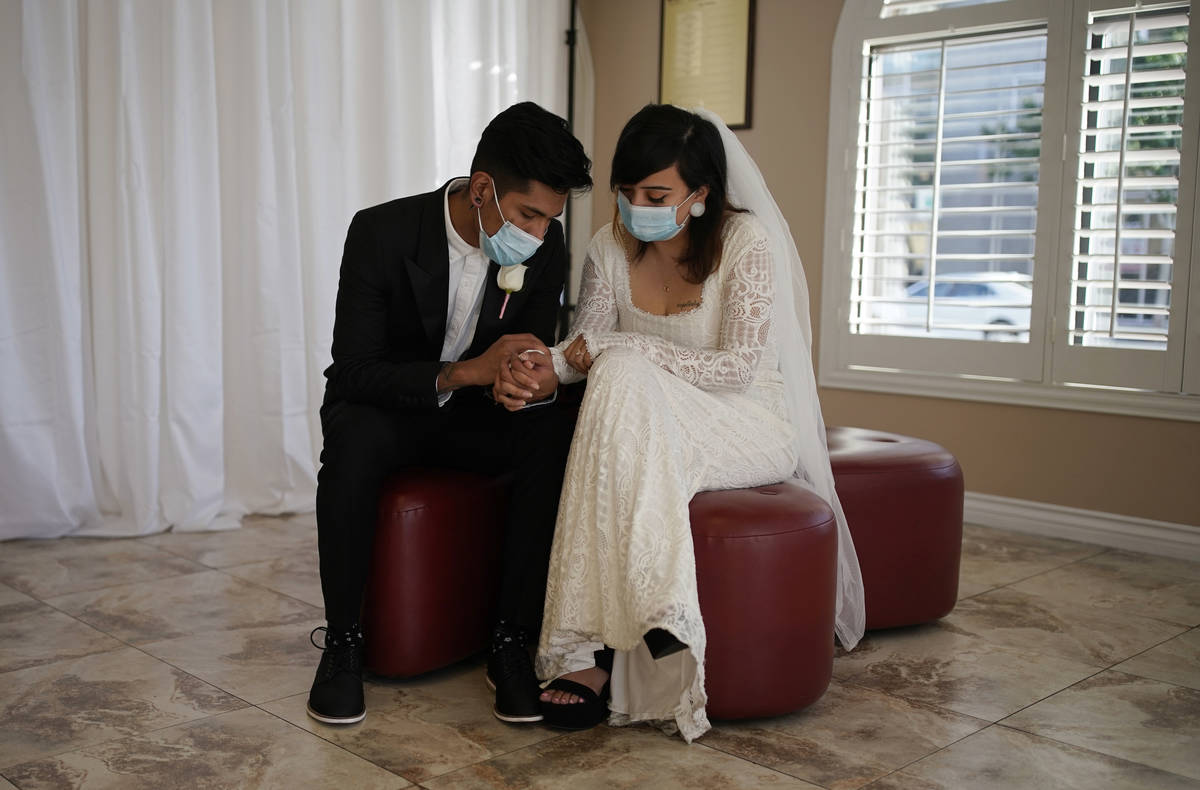 Angel Martinez, left, and Haillie Bernal hold hands while wearing masks as a precaution against ...
