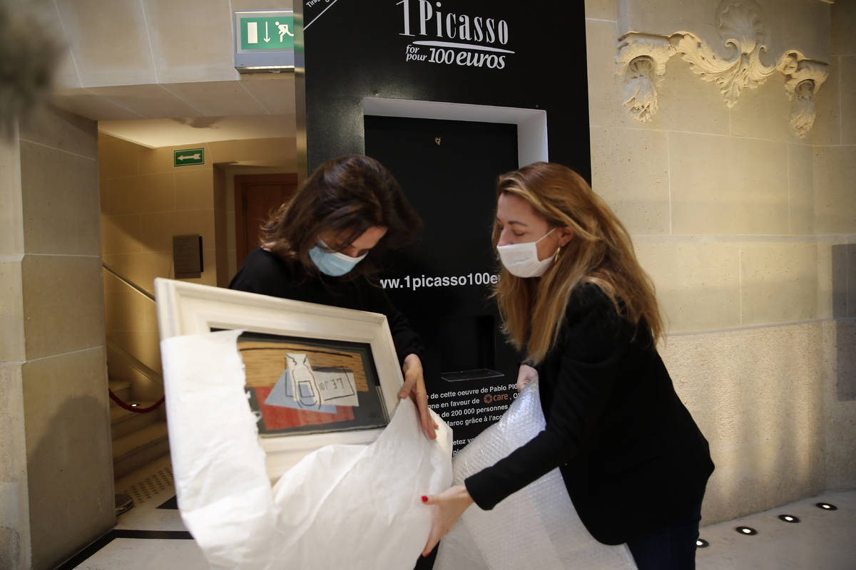 Raffle organizers Peri Cochin, left, and Arabenne Reille unbox the painting "Nature morte& ...