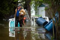 Mark Musselman brings a chair to the front of his house from the back yard, wading through floo ...