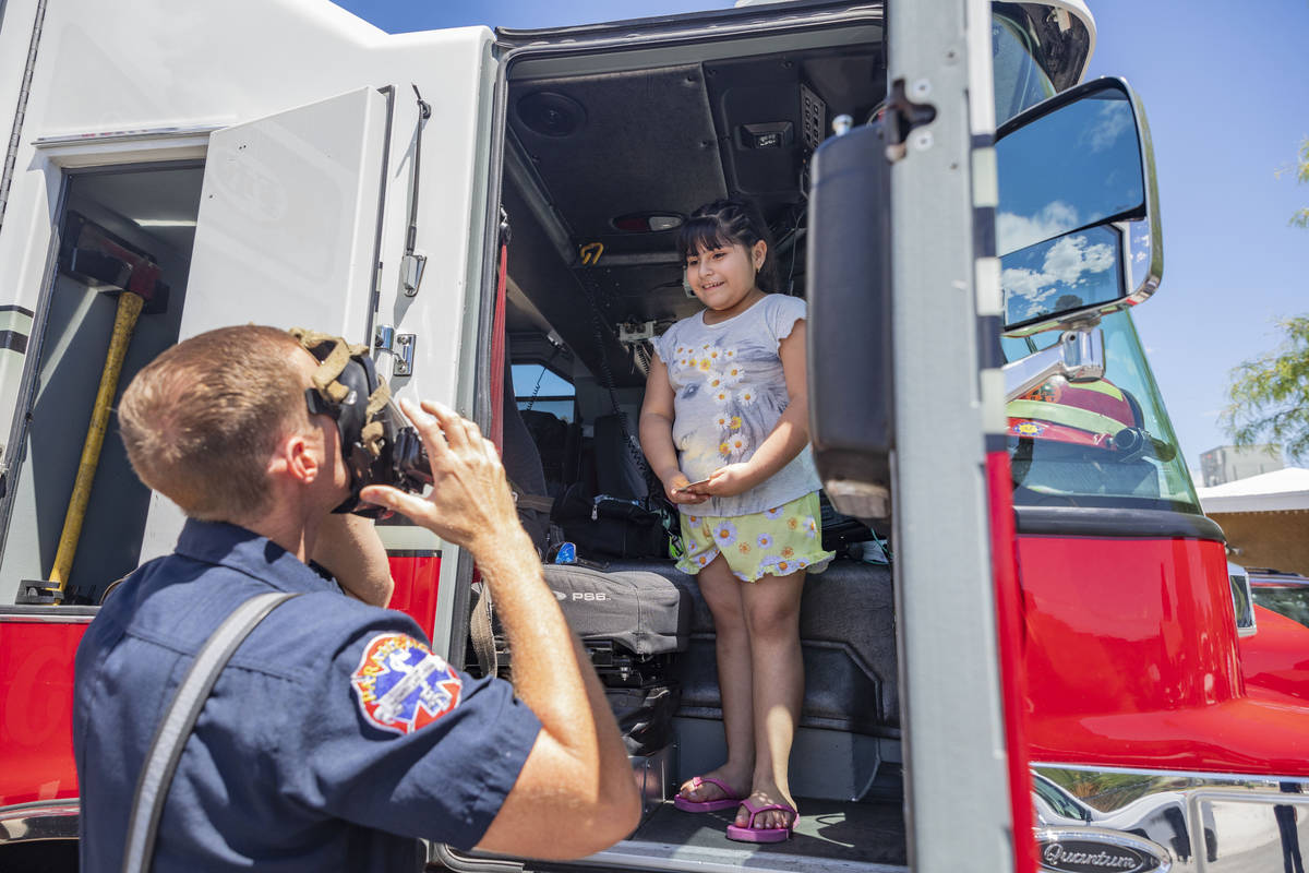 North Las Vegas Fire Capt. Ben Erickson shows his suit to Amy Nietl, 8, after her dad, Jose Alv ...