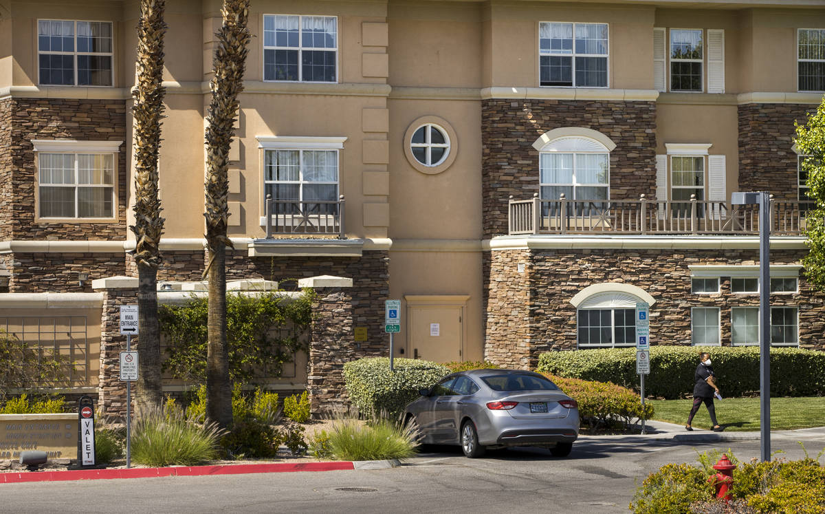 A woman walks outside of The Heights of Summerlin which has had numerous deaths there due to Co ...