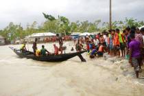 In this Wednesday, May 20, 2020 photo, a boat brings people to land, as locals check an embankm ...