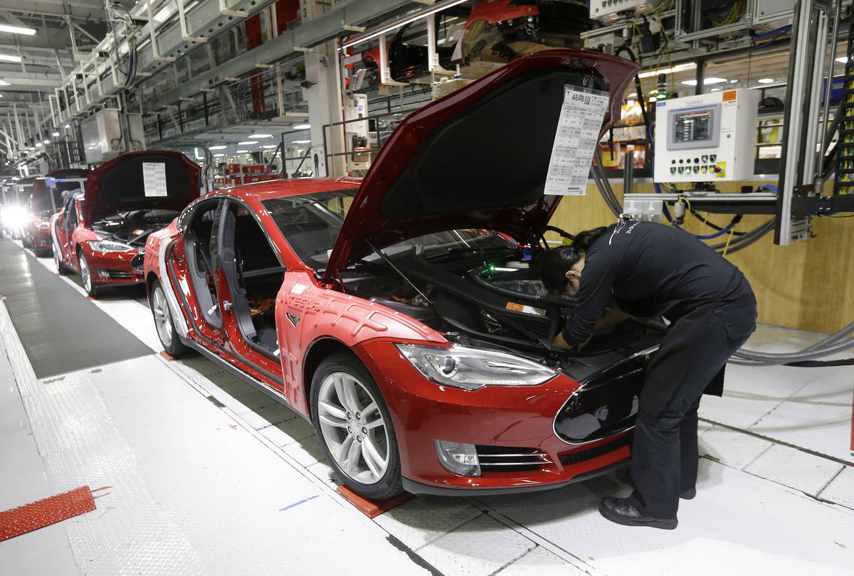 FILE - In this May 14, 2015, file photo, Tesla employees work on a Model S cars in the Tesla fa ...