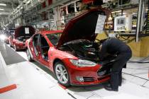 FILE - In this May 14, 2015, file photo, Tesla employees work on a Model S cars in the Tesla fa ...