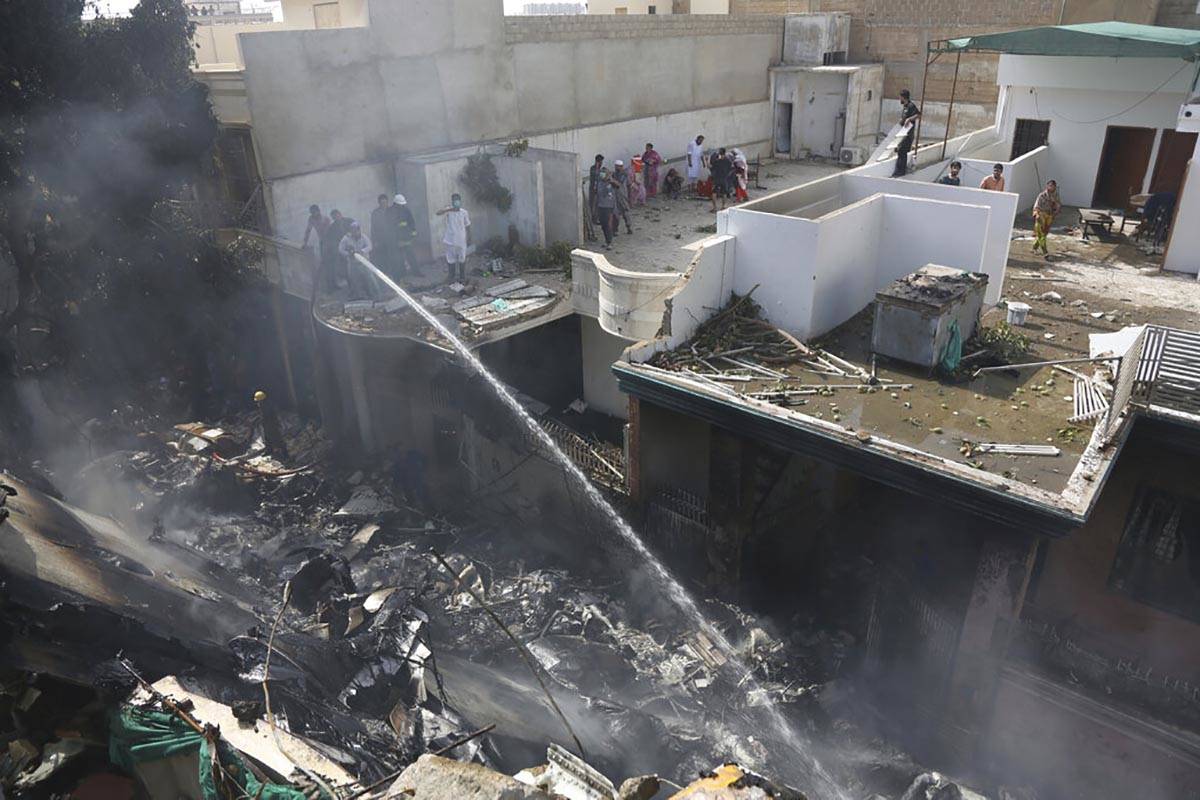 Fire brigade staff try to put out fire caused by plane crash in Karachi, Pakistan, Friday, May ...