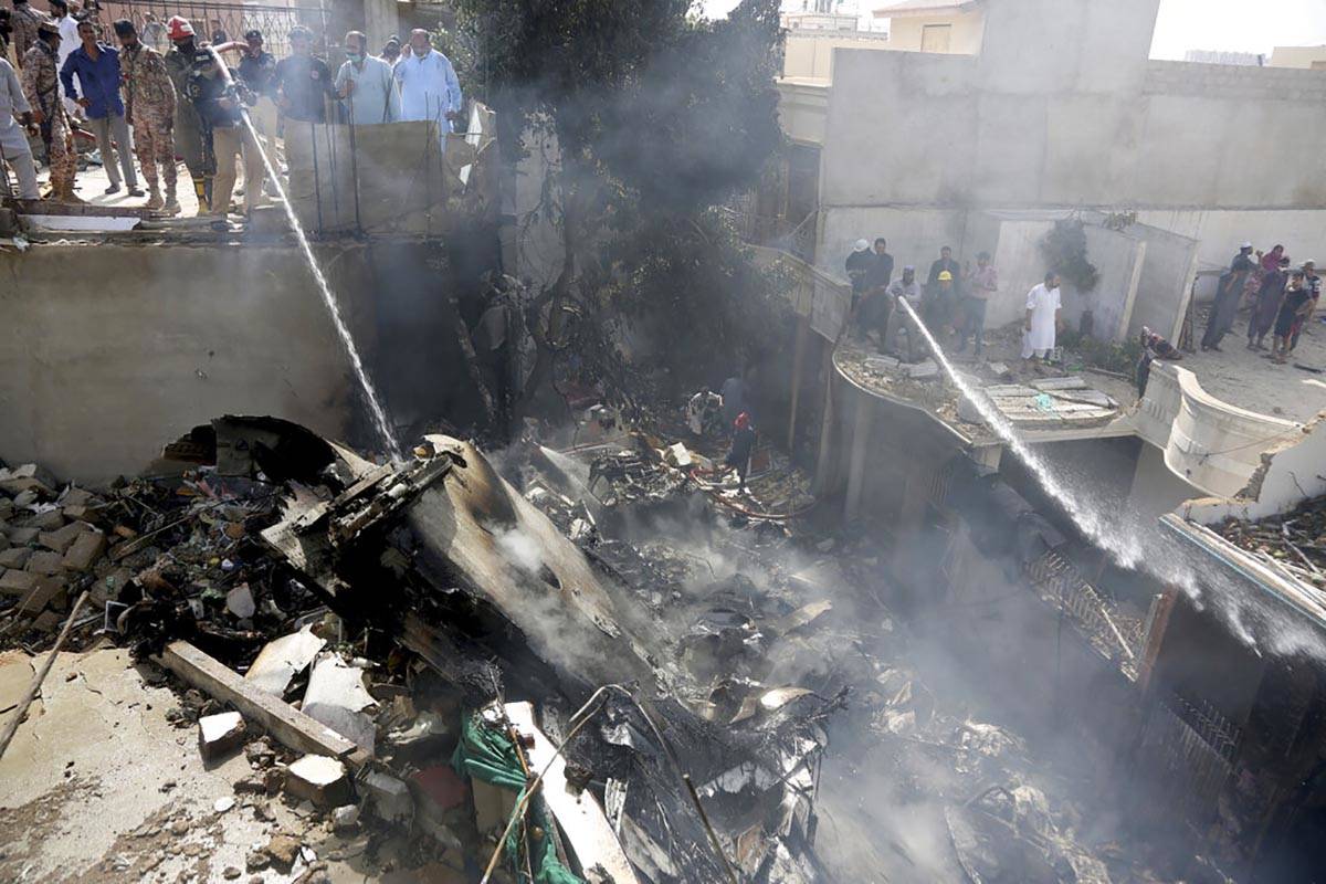 Fire brigade staff try to put out fire caused by plane crash in Karachi, Pakistan, Friday, May ...