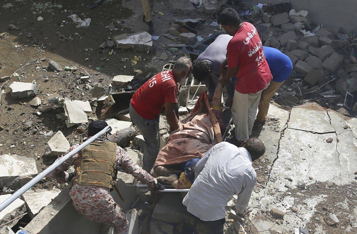 Volunteers carry the dead body of a plane crash victim at the site of a crash in Karachi, Pakis ...