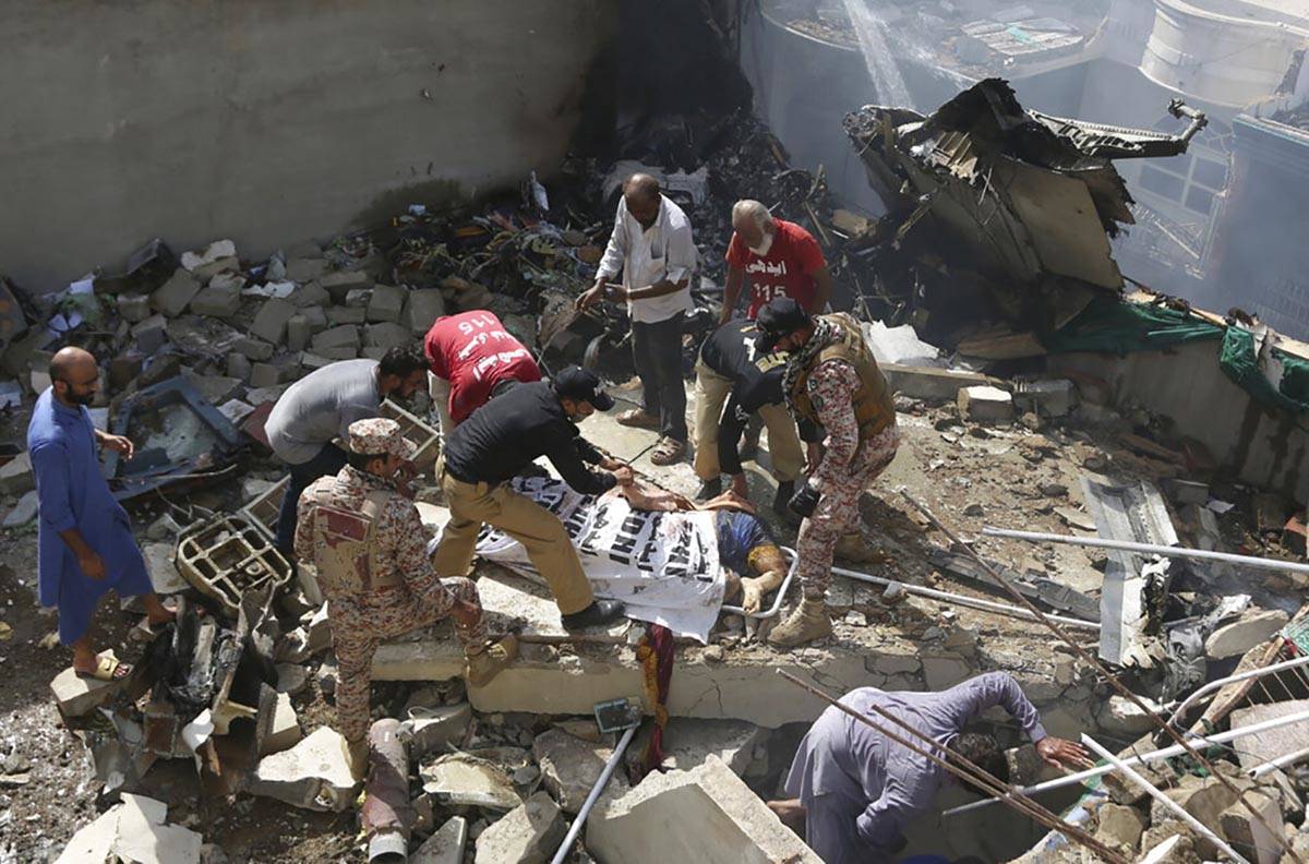 Volunteers cover the dead body of a plane crash victim at the site of the crash in Karachi, Pak ...