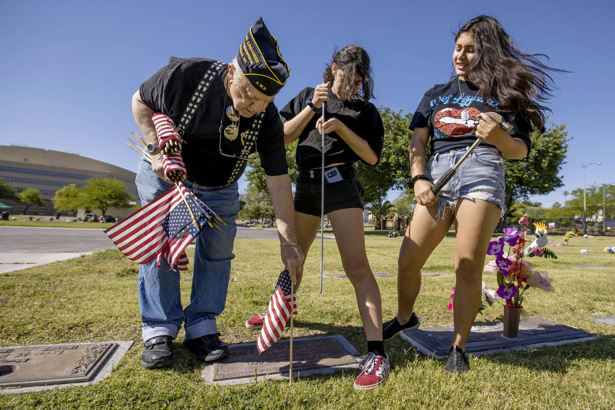 Army veteran Howard Greenspon, left, plants another American flag on a veteran's grave with the ...
