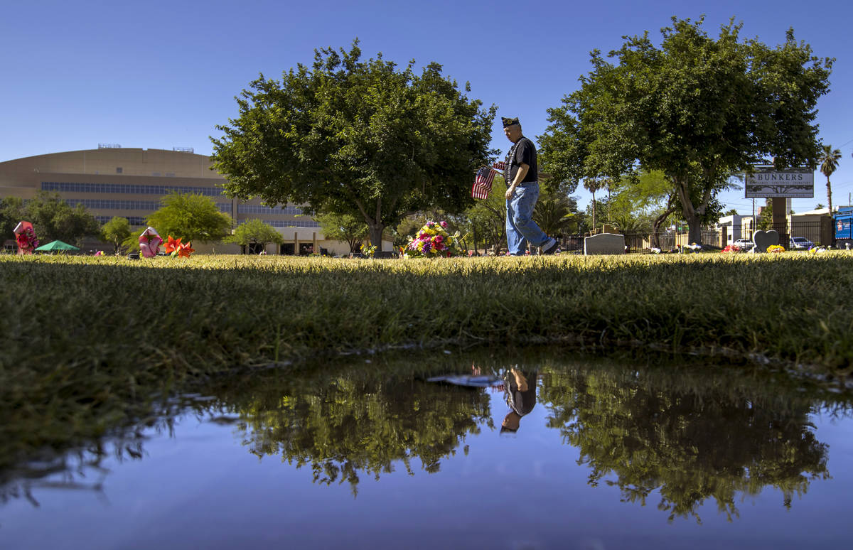 Army veteran Howard Greenspon is reflected in a small water puddle while looking to identify ve ...