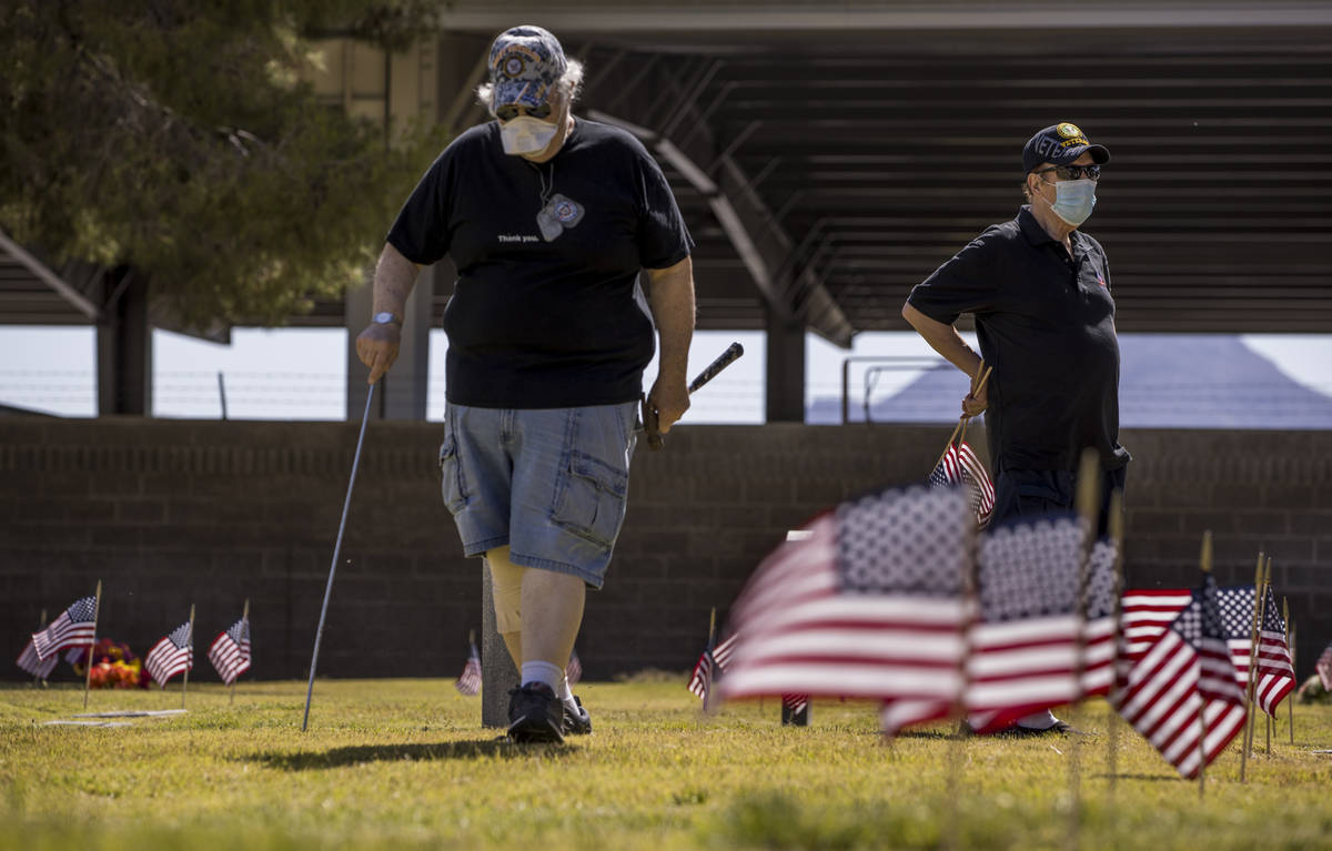Marvin Botwinik, left, and Brendan Vargas help plant more American flags on veteran's graves in ...