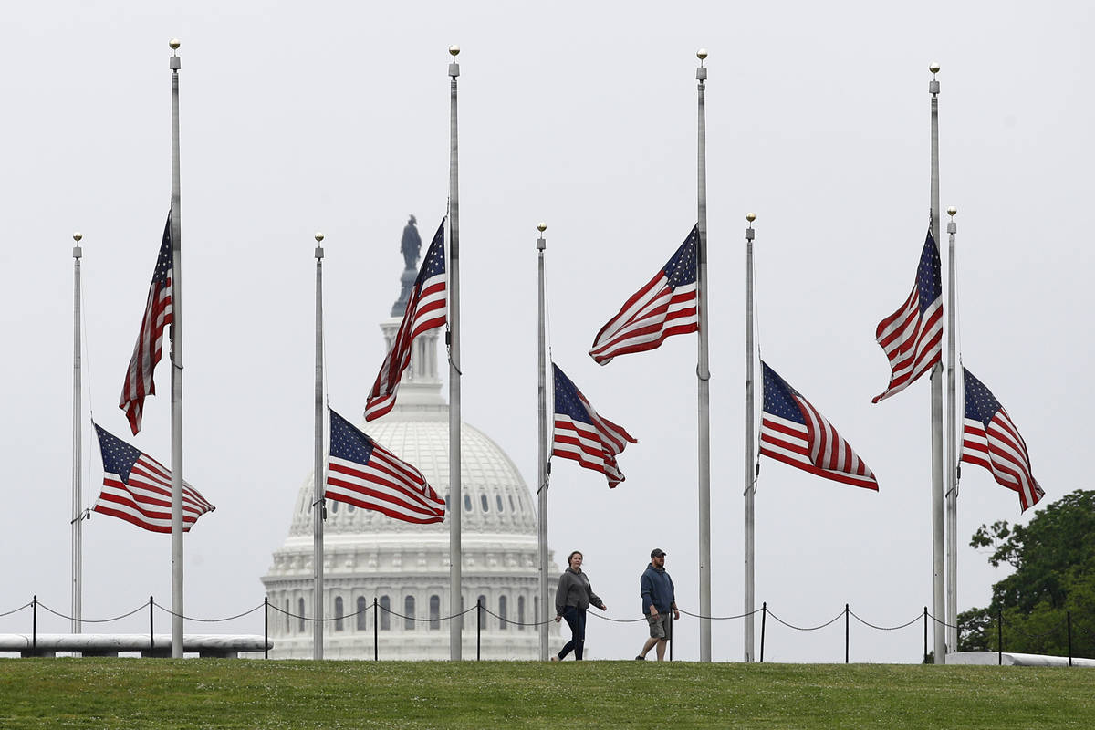 People walk past American flags flying at half-staff at the Washington Monument, Friday, May 22 ...