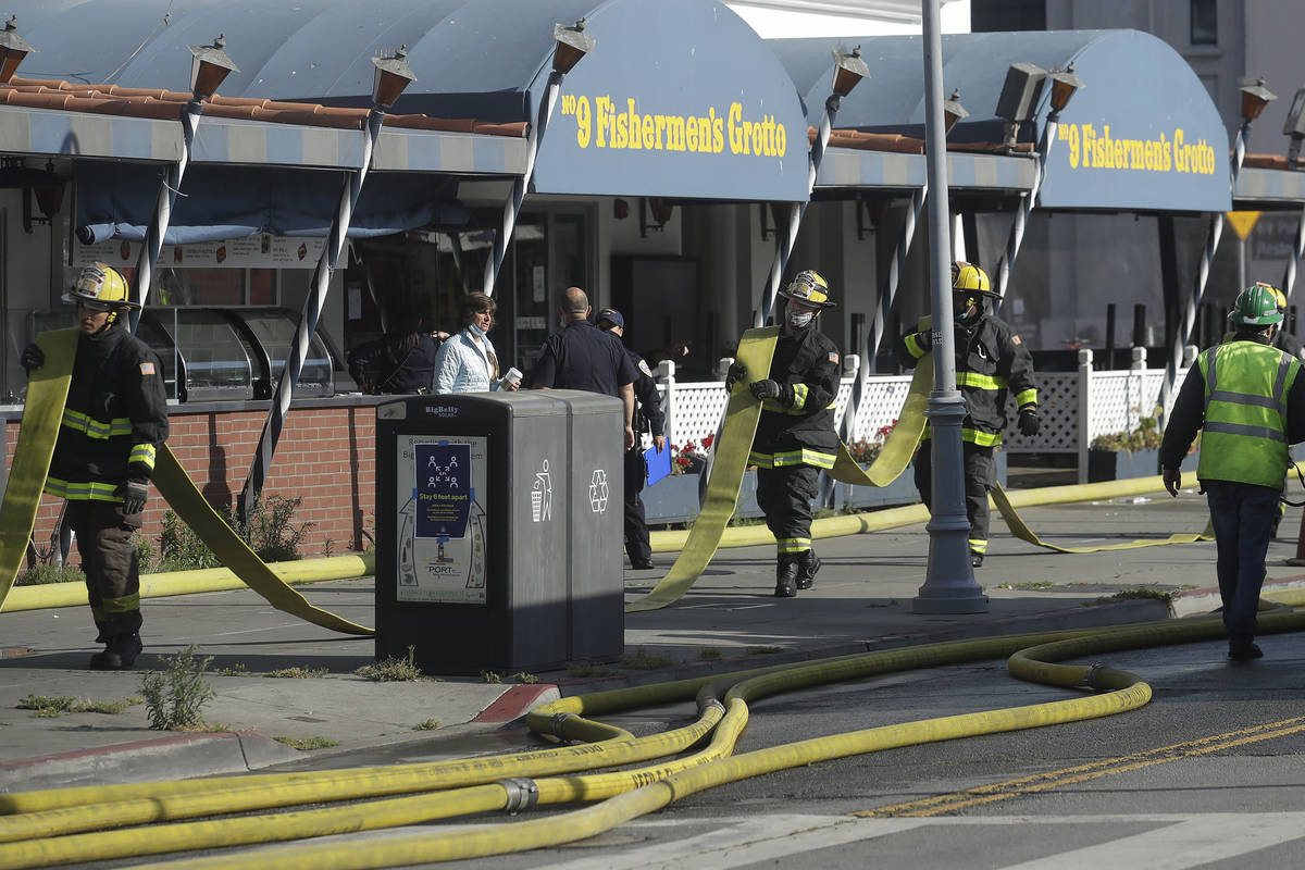 Fire officials carry a hose in front of The Grotto restaurant after a fire broke out before daw ...
