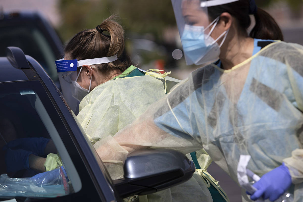 One volunteer swabs a patient's nose as another places information and a bible on their dashboa ...