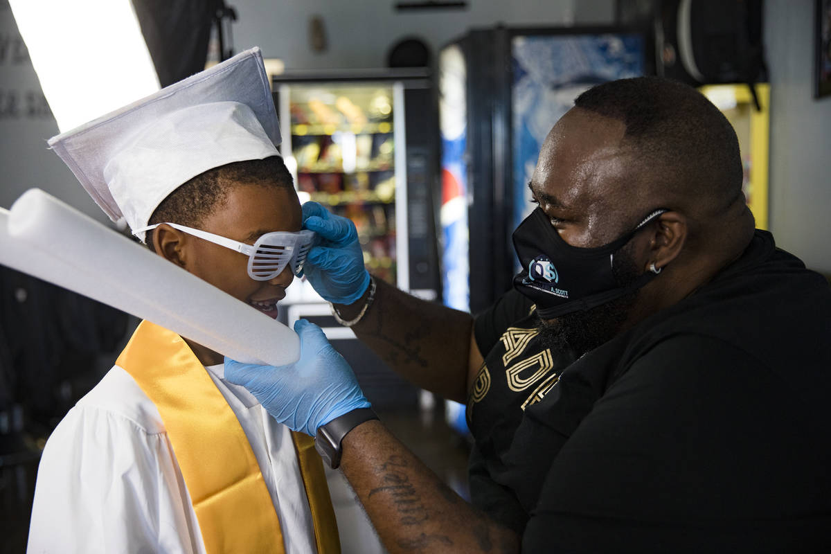 Dr. Dillard A. Scott puts glasses on Jourdyn Carson, 6, for his kindergarten graduation photo a ...