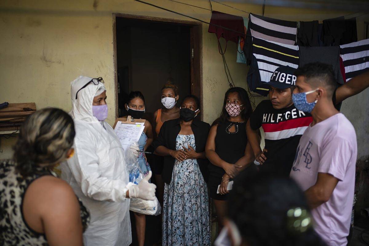 Relatives and friends of the late Eldon Cascais talk to a SOS Funeral worker wearing protection ...