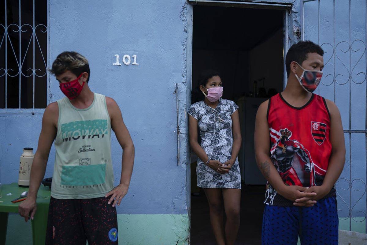 Caregiver Leandro Beiton, left, and relatives of the late Edgar Silva, wearing face masks amid ...