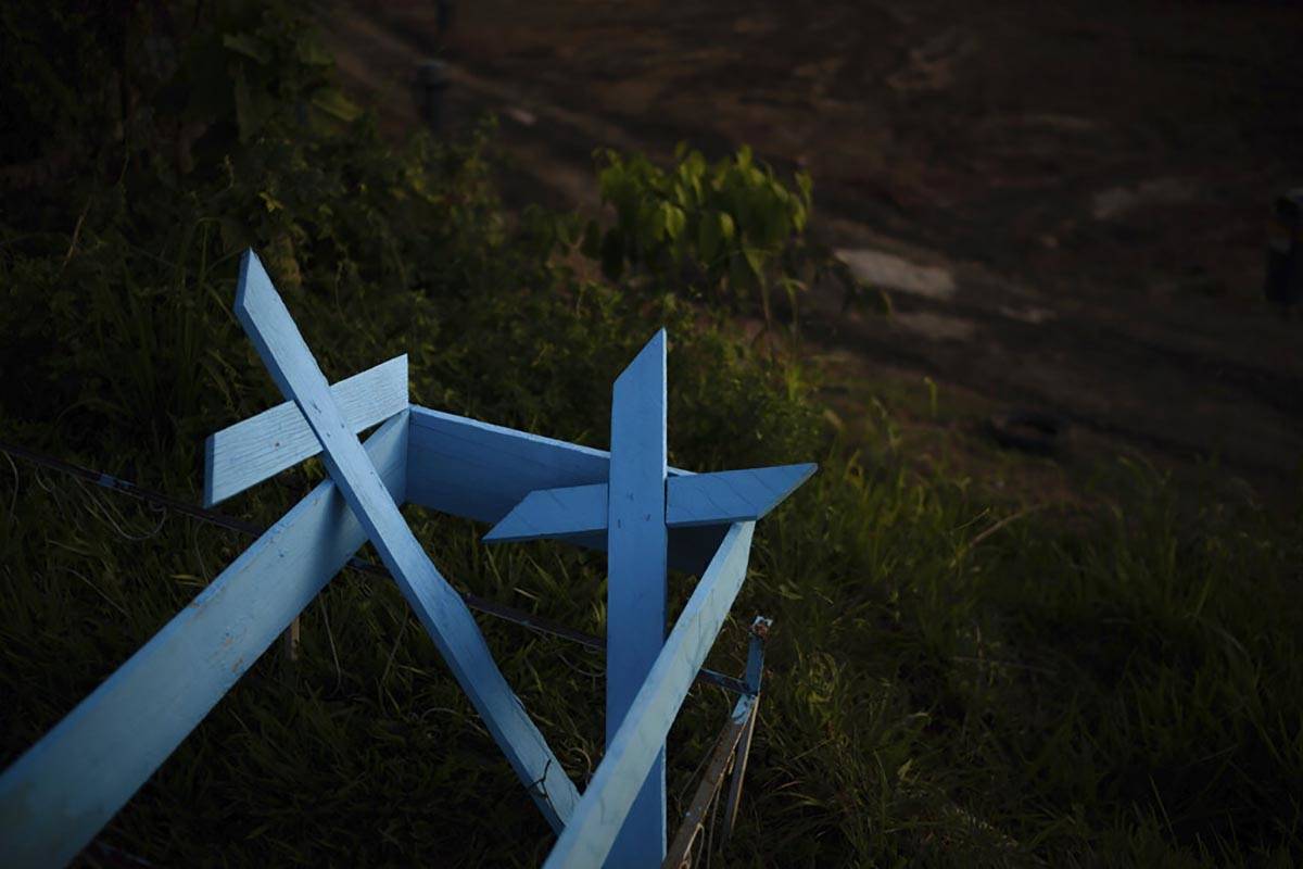 Painted wooden crosses lay on the roadside of a new section of the Nossa Senhora Aparecida ceme ...
