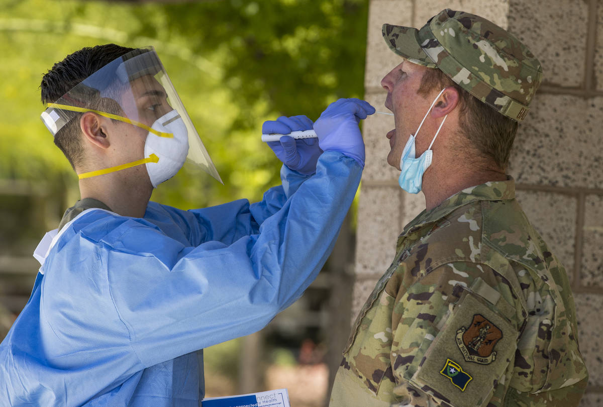 Nevada National Guard soldier PFC Nikolas Herrera, left, inserts a swab into the mouth of Lt. C ...