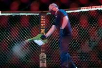 A worker sprays sanitizer in the octagon between bouts during a UFC 249 mixed martial arts comp ...