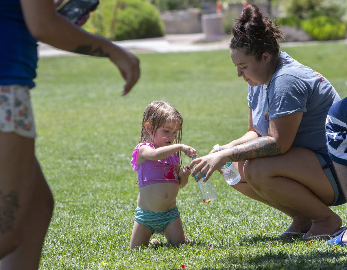 Aaliyah Merrick, 3, picks up balloon pieces with Julianne Tuttle after a water balloon fight at ...